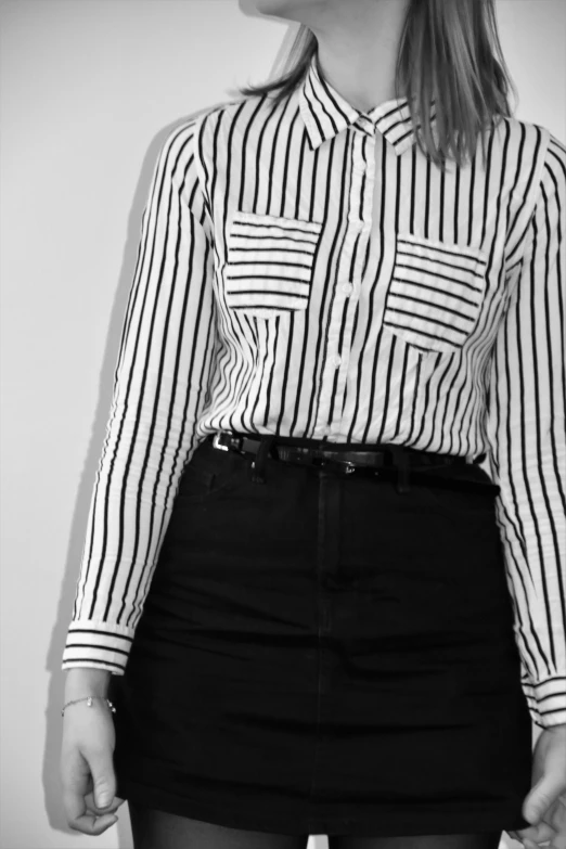 black and white pograph of woman in short skirt looking down at her shirt