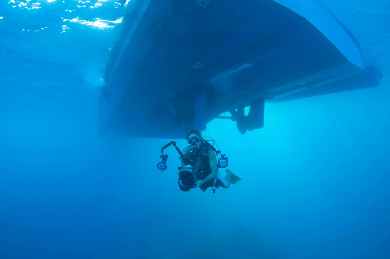 diver in the blue water, under the sailboat