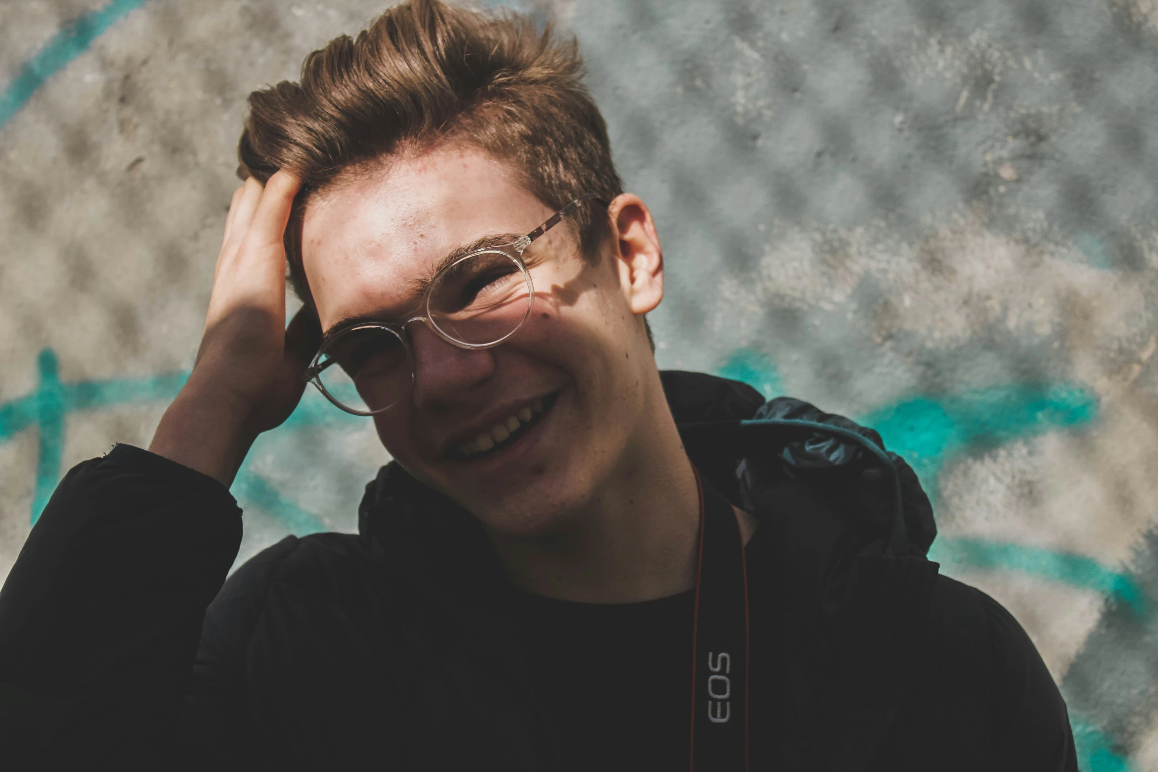 a man smiling while wearing sunglasses and a backpack