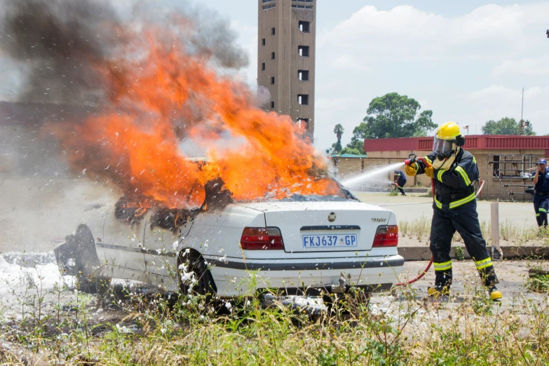 a fireman extinguishes flames at the burning car