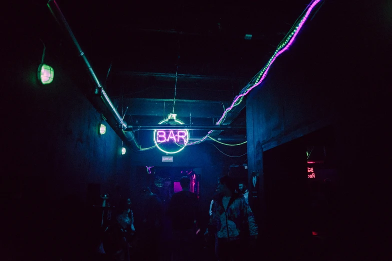 people walking in the dark, lit hallway of a bar