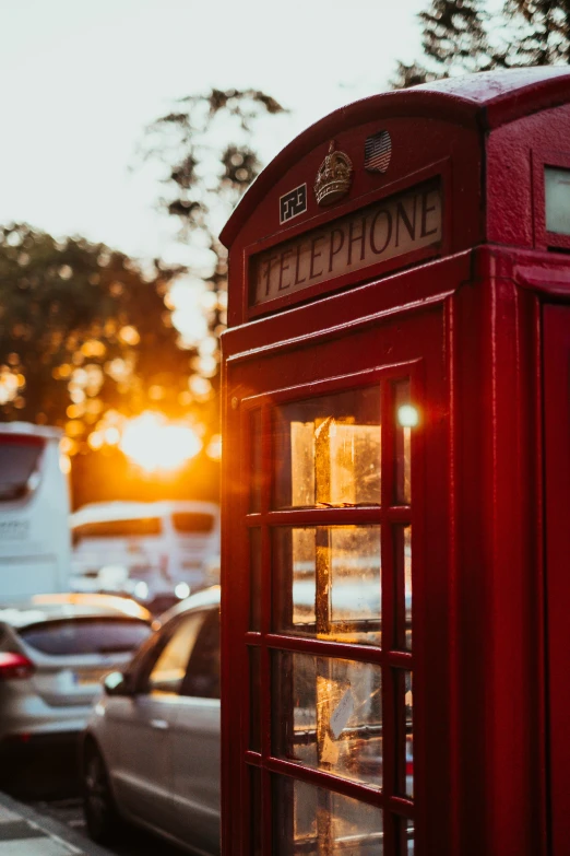 a red phone box is seen in front of cars