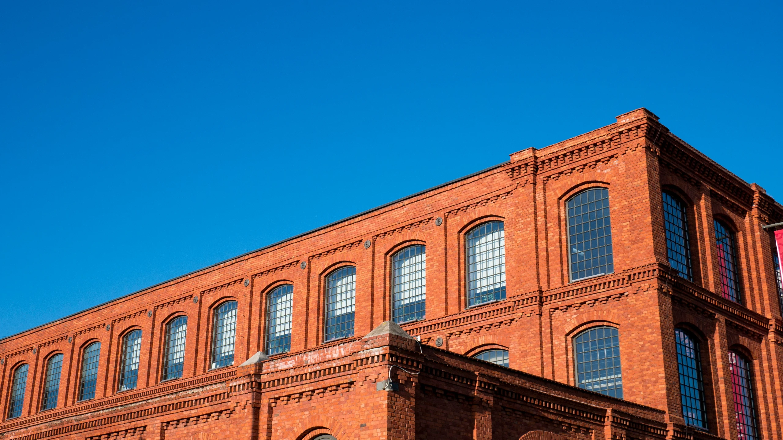 the side of an old red brick building, with no clouds in the sky