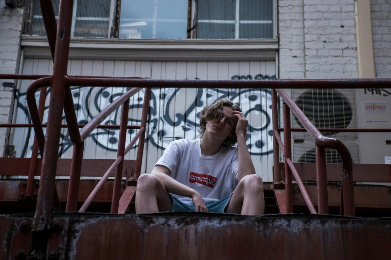 a young man wearing sunglasses and sitting on a rail