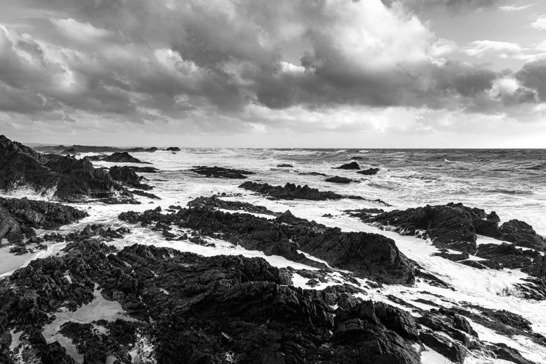 an ocean with rocks under a cloudy sky