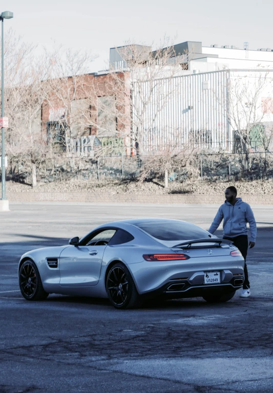 a man standing next to a silver sports car