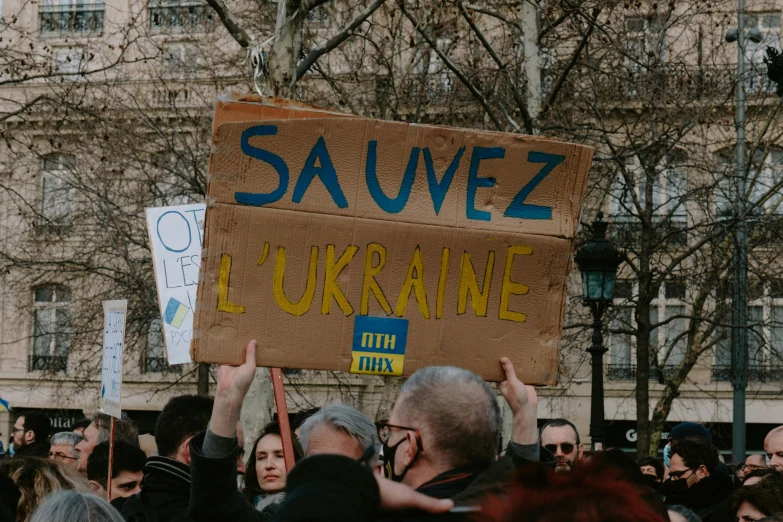 a group of people holding up signs in front of some buildings