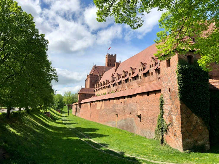 there is a large red brick building near a grass field