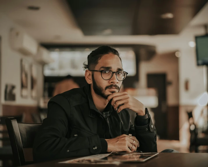 a man sitting at a restaurant table with a laptop in his lap