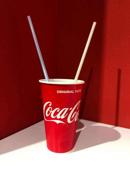 a cup that has straws in it and a red wall behind