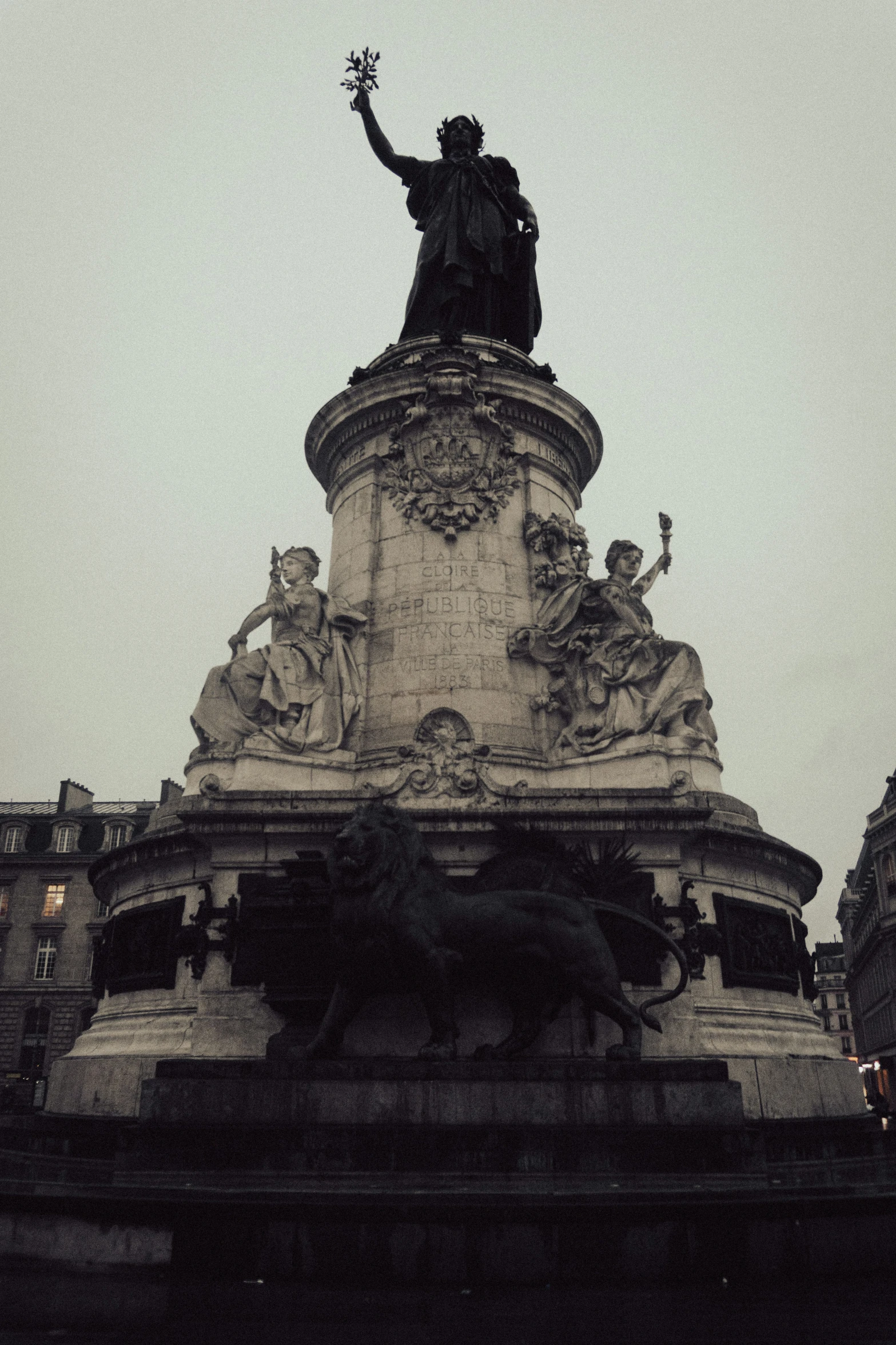 a statue on top of a building next to a tall tree