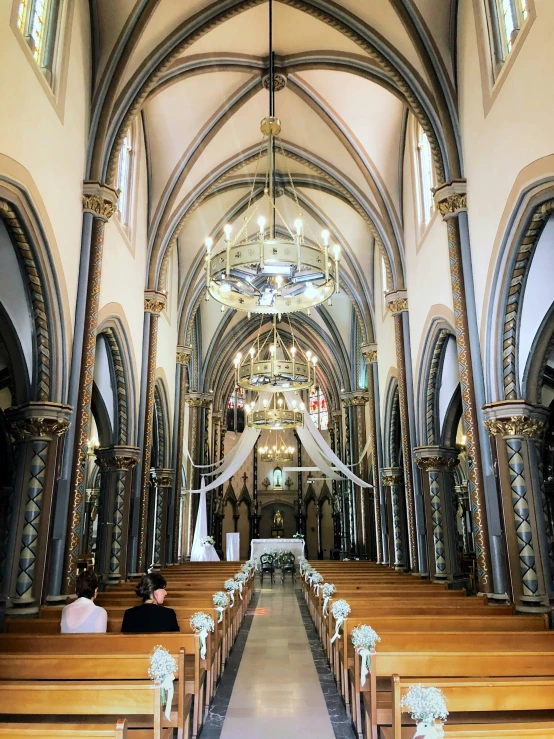 inside of a church with multiple benches, tall arches and a long aisle