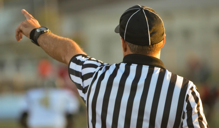 a referee pointing to soing while looking to his right