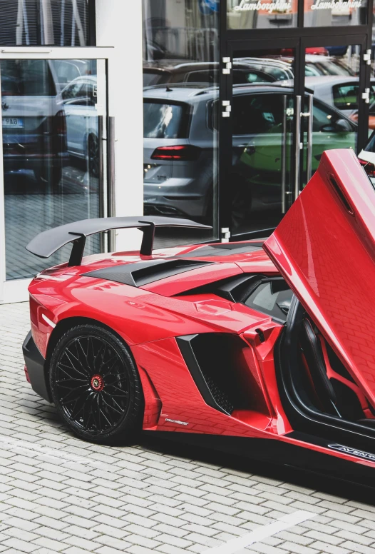 red car with open doors is parked on the street