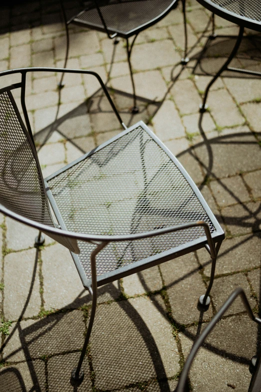 two chairs and one table outside on the sidewalk