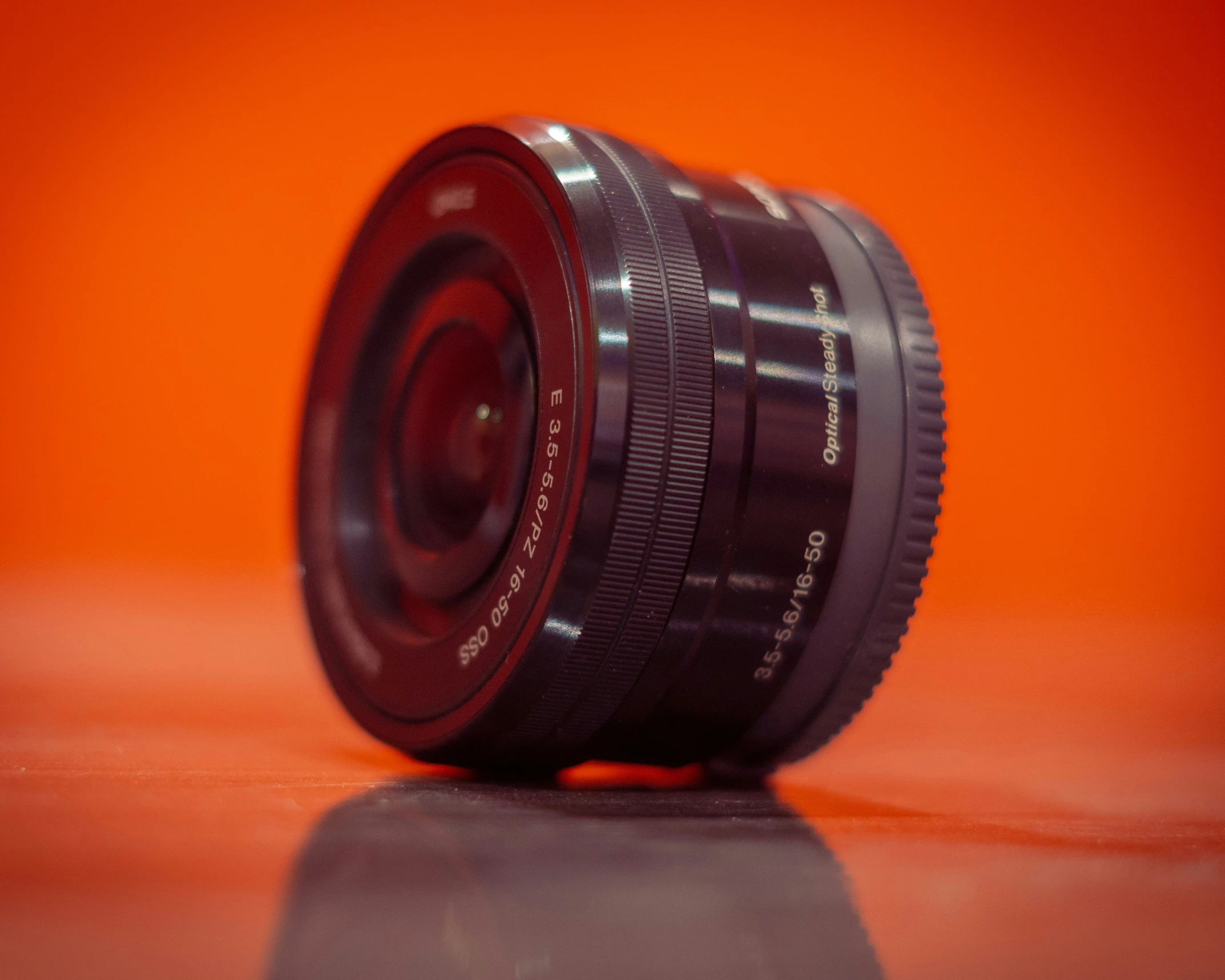 a camera lens sits on the floor in front of a plain background
