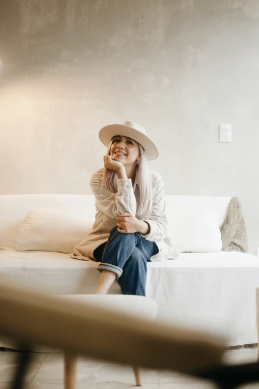 a girl sitting on the couch with a hat on