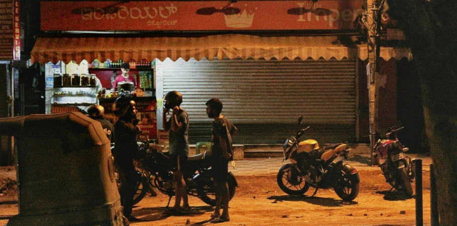 a motorcycle is parked behind two men standing in front of an opened shop