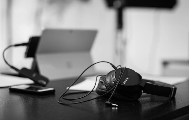 black and white po of headphones sitting on a desk