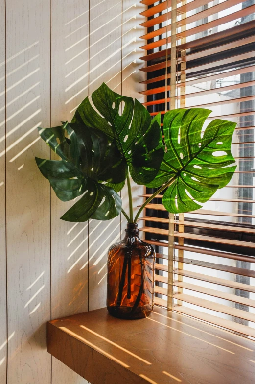 a brown vase with a green plant sitting on a table