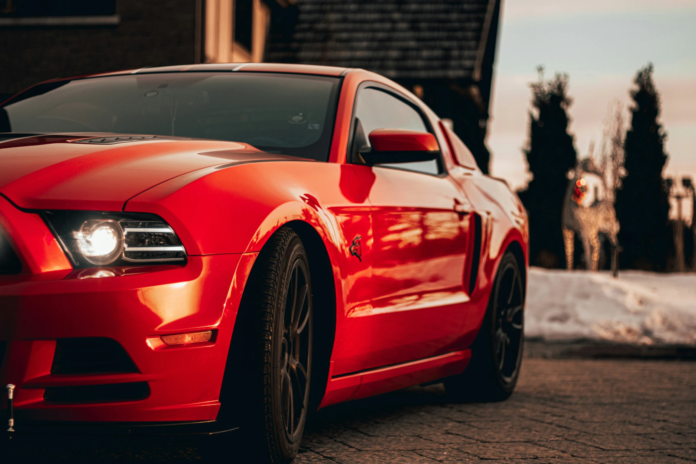 the front end of a red mustang in a driveway