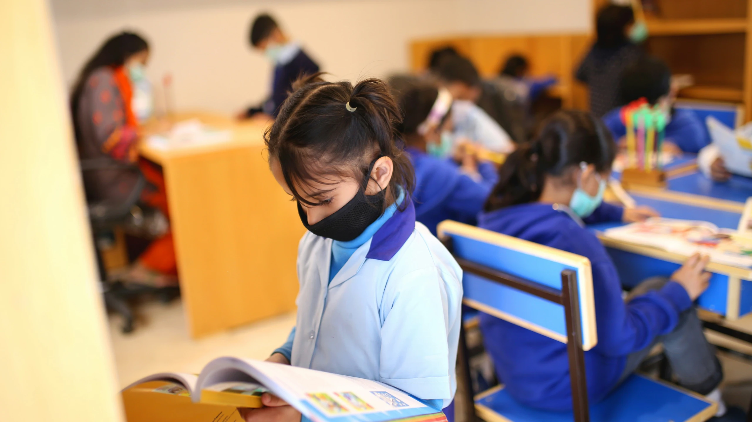 a classroom with many students in blue uniforms sitting at desks