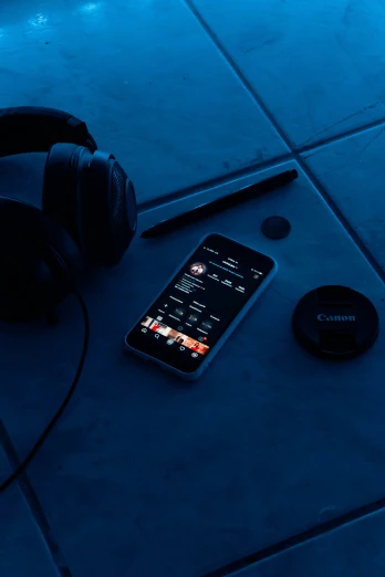 a black phone next to some headphones on a floor