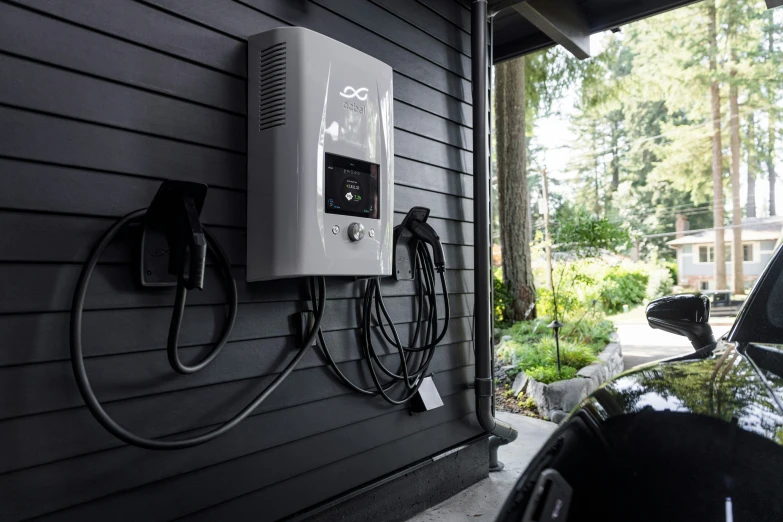 an electric car plugged into the charger on a gray house