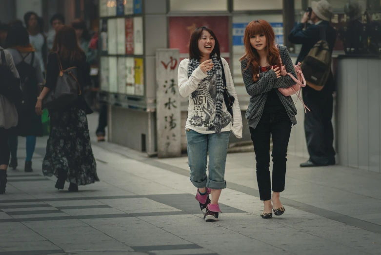 two ladies walking in an asian city on their cell phones