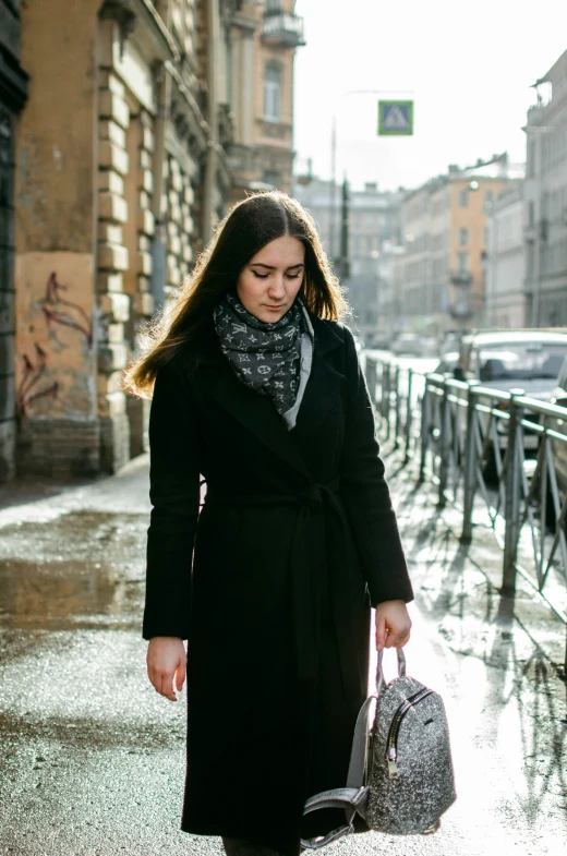 a woman in black coat walking down the street