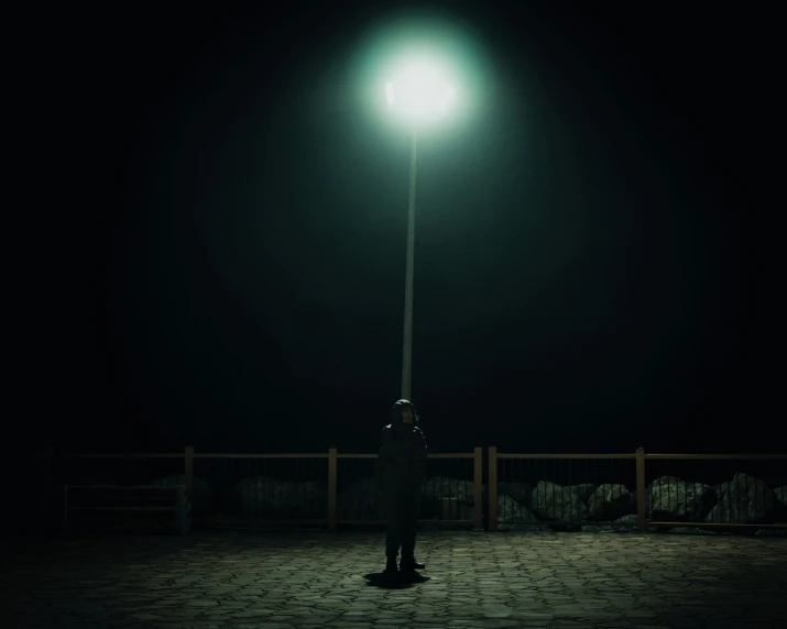 a person is standing in the dark by a street light