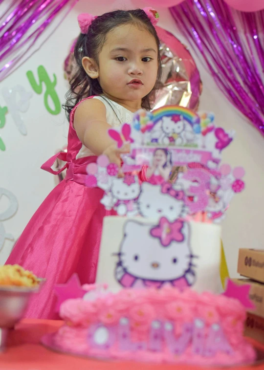 a  reaches for a cake that has hello kitty on it