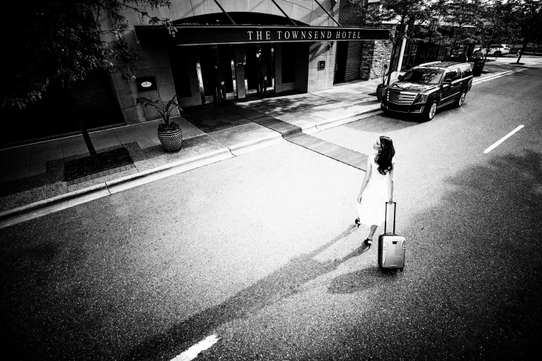 a woman walking down the road with her luggage