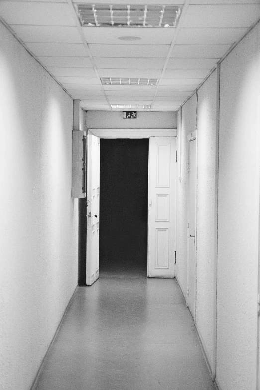 a hallway with a sign in the middle and a door with a light on it