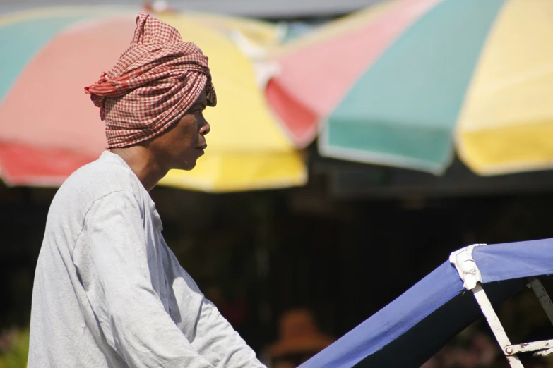 a person in white shirt and turban walking next to umbrellas