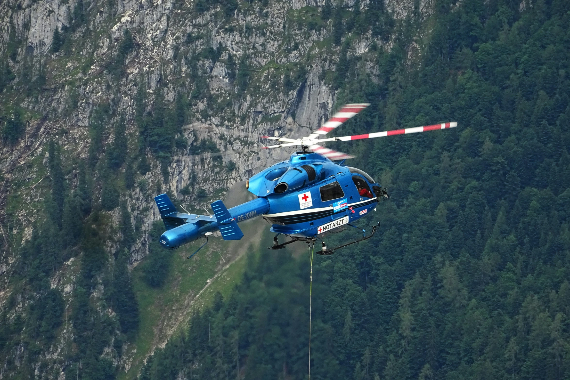 a helicopter is flying near mountains and a mountain