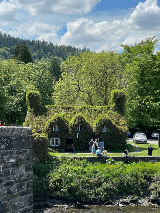 some people by a body of water next to small buildings