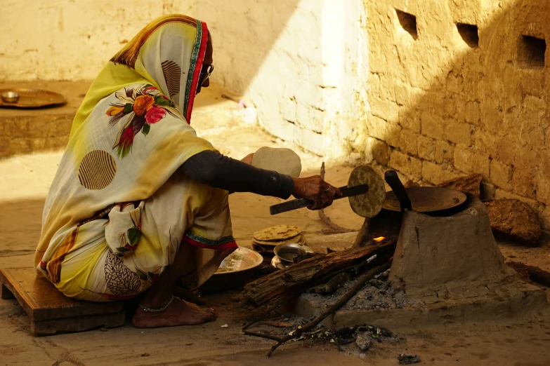an old woman sitting down as she cooks soing on a stove