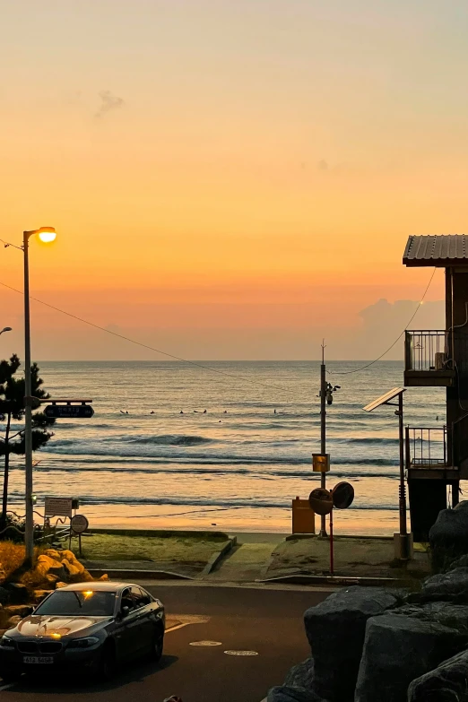 a beautiful sunset near an ocean with cars parked at the shore