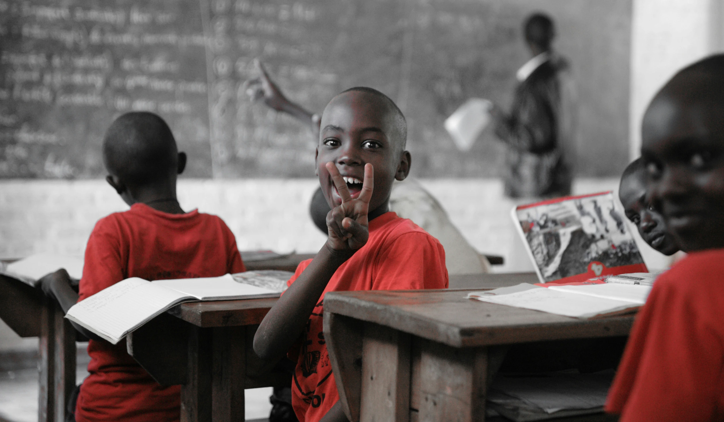 two boys in red shirts in front of desks