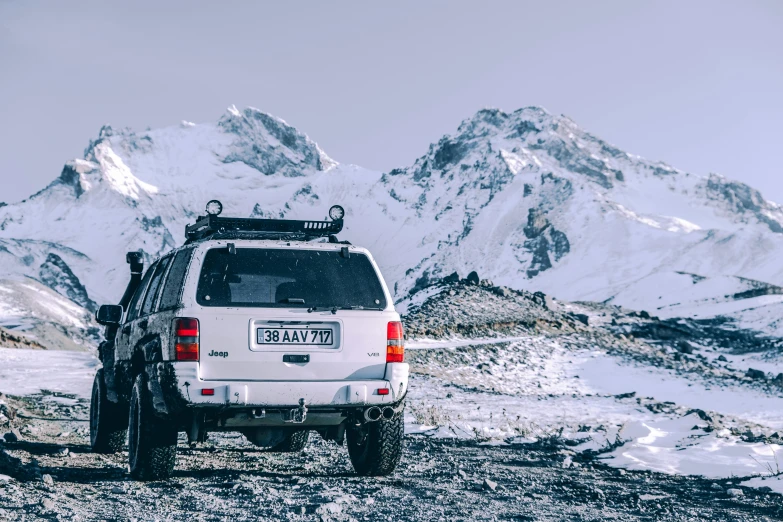 an suv with large tires in the snow covered mountain pass