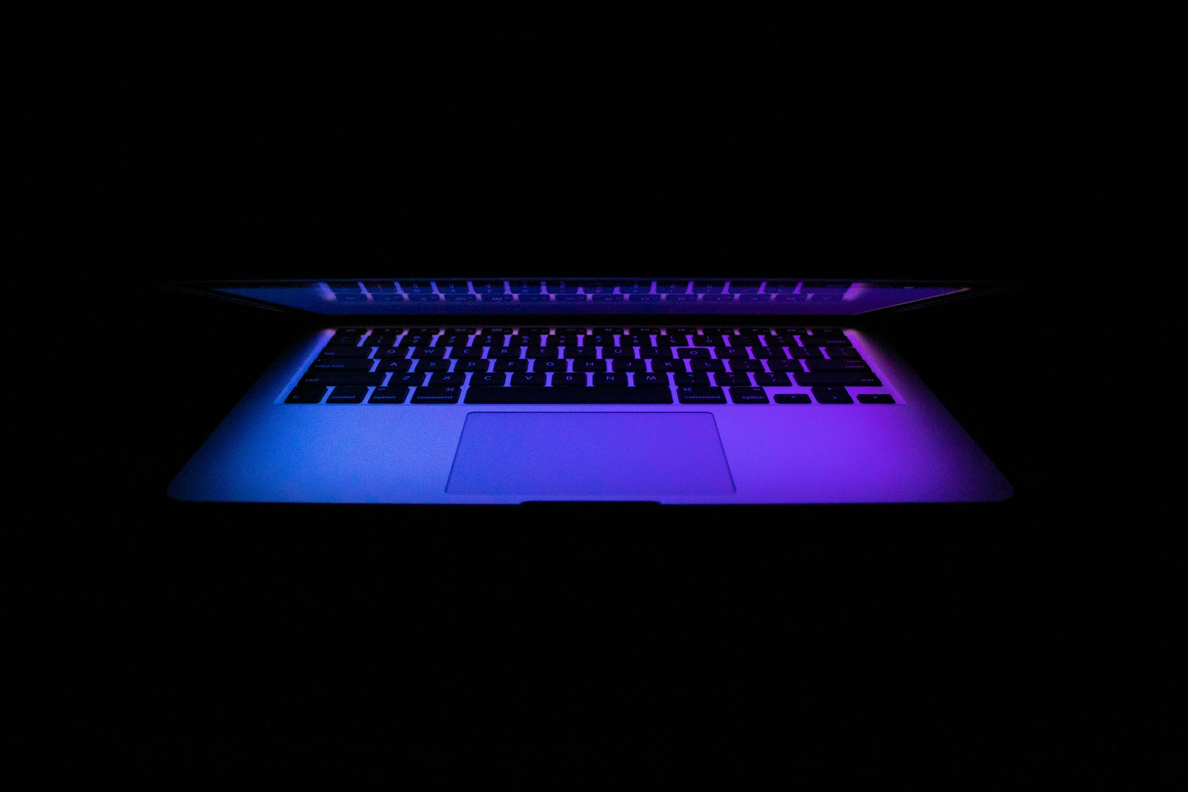 an apple macbook pro with its glowing keyboard