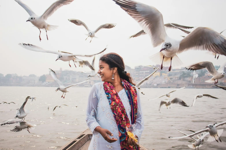 woman on a pier surrounded by a flock of seagulls