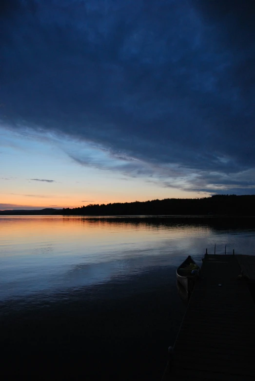 a row boat is sitting on a pier near the lake