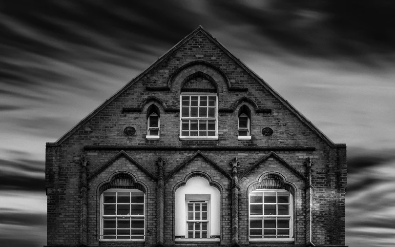 a dark house with white windows and dark skies