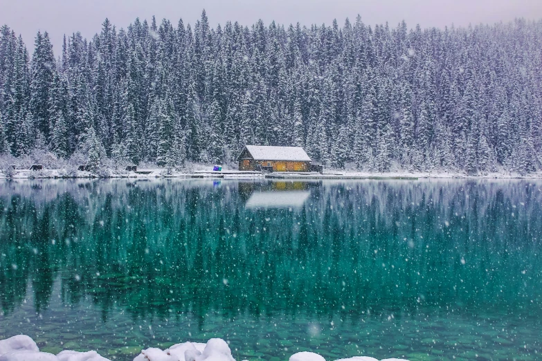 a snow covered cabin sits in front of a lake