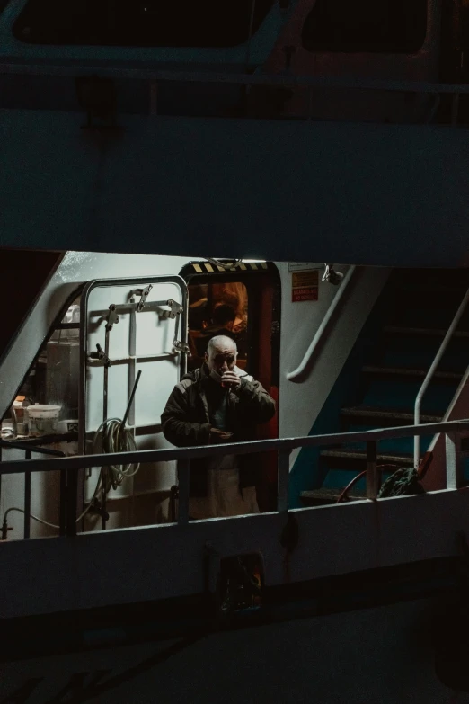 man in dark room on a boat with railing