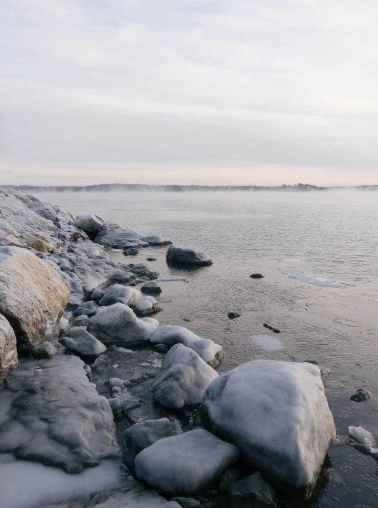 a rocky shore line is covered with ice