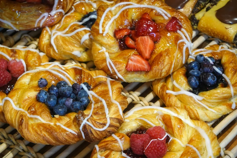 pastry pastries topped with berries and frosting sitting on a rack