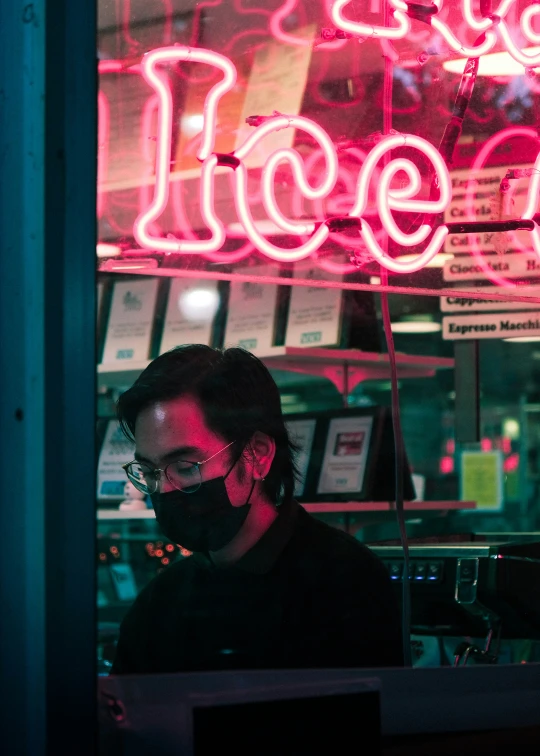 a man in a protective mask standing in front of a neon sign that reads ice cream